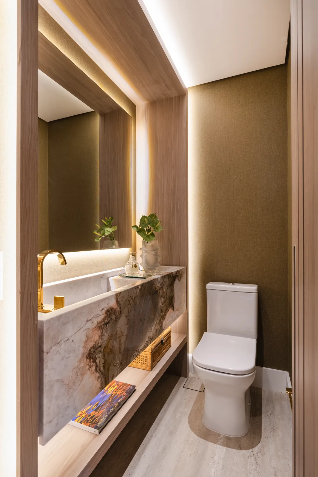 Lavabo com bancada de pedra exótica e parede em tecido dourado